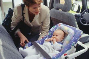 Mother putting baby in car seat