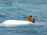 In this photo released by the U.S. Coast Guard, shows former University of South Florida football player Nick Schuyler clinging to the engine of an overturned boat in the Gulf of Mexico, as the U.S. Coast Guard approaches, Monday March 2, 2009. (AP Photo/U.S. Coast Guard,HO)