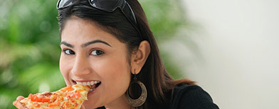 Woman biting into pizza slice. (Getty Images)