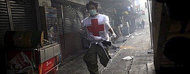 A medic runs for cover in Bangkok street. (AP Photo/Wong Maye-E)