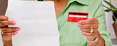 Woman with credit card bill. (Jupiterimages)