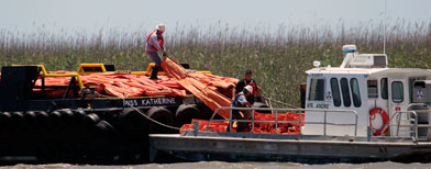 Workers off load an oil containment boom onto a smaller vessel near the mouth of the Mississippi River near South Pass, Thursday, April 29, 2010. (AP Photo/Bill Haber)