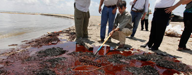 Louisiana Gov. Bobby Jindal pushes a rake through washed up oil and absorbent material as he tours a land bridge built by the Louisiana National Guard to hold back oil from the Deepwater Horizon oil spill in Grand Isle, La., Friday, May 21, 2010. (AP Photo/Gerald Herbert)