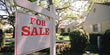 For sale sign hanging in front of house (Thinkstock)