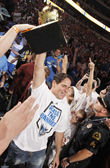 Mavericks owner Mark Cuban carries the Larry O'Brien Trophy to the stage during the victory celebration on Thursday.