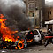 An Egyptian anti-government protester throws a traffic cone into a burning car in front of a burning police station in Giza, Egypt. (AP/Victoria Hazou)