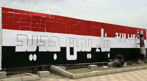 Anti-government protestors work on a billboard with Yemen's flag and Arabic words that read,