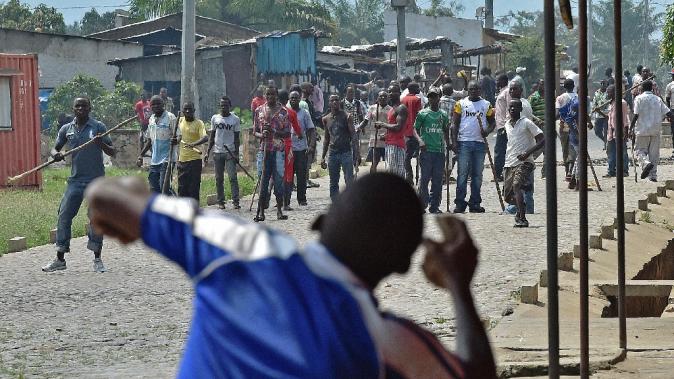 A protestor opposed to the Burundian President&#39;s third term throws a rock at members of the Imbonerakure, the youth wing of the ruling party, armed with sticks in the Kinama neighborhood of Bujumbura on May 25, 2015