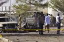 Bomb detection experts and members of the military stand at the scene of an explosion at a police station in Kano