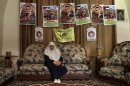 In this Thursday, May 10, 2012 photo, Dalal, mother of Mohammed al-Taj, sits underneath posters showing her son at their family house in the West Bank village of Tubas. Muhammed al-Taj is jailed in Israel and is on a hunger strike since March 15, 2012. (AP Photo/Bernat Armangue)