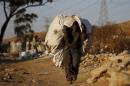 An unemployed man carries a bag full of recyclable waste material which he sells for a living, in Daveland near Soweto