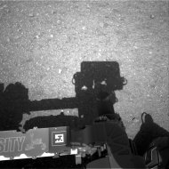 This image released by NASA on Wednesday, Aug. 8, 2012, shows the edge of NASA's Curiosity rover, showing the shadow of the rover's now-upright mast in the center, and the arm's shadow at left. The navigation camera is used to help find the sun -- information that is needed for locating, and communicating, with Earth. (AP Photo/NASA)