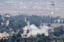 The Syrian flag flies in the village of Quneitra, as seen from the Israeli-occupied Golan Heights, as smoke billows during fighting between forces loyal to Syrian President Bashar Assad and rebels on August 29, 2014