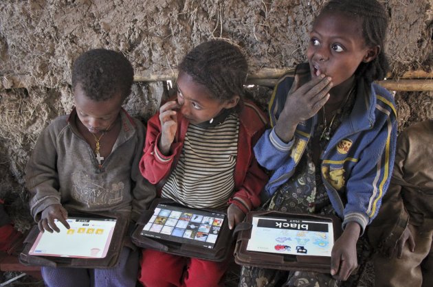 In this photo taken Tuesday, Nov. 27, 2012, children play with tablet computers given to them by the One Laptop Per Child project in the village of Wenchi, Ethiopia. The project gave tablets to the children in the poor, illiterate village to see how much the children could teach themselves and now many kids can recite the English alphabet and spell words in English. (AP Photo/Jason Straziuso)