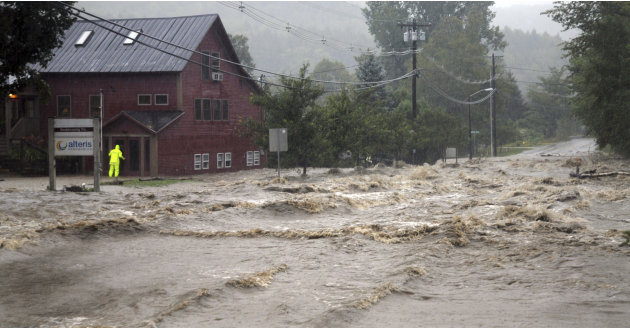 A person searches for anyone who may be occupying the building as raging flood waters from Tropical Storm Irene cross Route 100, closing the main road to traffic in Waitsfield, Vt., Sunday, Aug. 28, 2