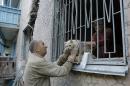 Valery who gave only his first name takes his suffered cat from his damaged house after shelling in the city of Slovyansk, Donetsk Region, eastern Ukraine Monday, June 30, 2014. Residential areas came under shelling on Monday morning from government forces. (AP Photo/Dmitry Lovetsky)