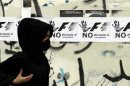 In this photo taken March 24, 2011, a Bahraini anti-government protester runs for cover during clashes with security forces in Sitra, Bahrain, during a demonstration against holding the April 22 Grand Prix in Bahrain, with a wall covered with anti-government graffiti and fliers opposing holding the race in Bahrain. The chief executive of the Bahrain International Circuit Sheik Salman bin Isa Al-Khalifa said Wednesday March 28, 2012, that 