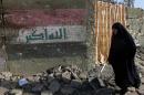 An Iraqi woman walks past a damaged building on September 19, 2014, a day after a suicide car bombing and shelling struck the Shiite shrine district of Kadhimiyah in Baghdad