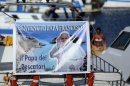 A banner depicting Pope Francis with the words, "Welcome Pope - The Pope of fishermen" is displayed on a boat in Lampedusa