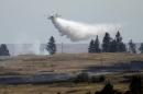 A firefighting plane drops water from Fishtrap Lake on a stubborn fire burning near the lake in Lincoln County, Sunday, July 20, 2014, near Cheney, Wash. The fire started Saturday afternoon and spread to several thousand acres, driven by high winds. (AP Photo/The Spokesman-Review, Jesse Tinsley) COEUR D'ALENE PRESS OUT