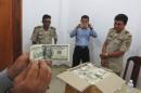 Police and court officials examine notes from a seized haul of $7.16 million in counterfeit hundred-dollar bills, in Battambang