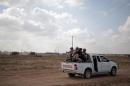 In this Wednesday, June 10, 2015 photo, Palestinian Hamas gunmen ride on the back of a pick-up truck as they patrol the border with Israel near the southern Gaza Strip town of Khan Younis, as Israeli military bulldozers are seen in the background. Nearly a year after a devastating war, Israel and Gaza's Hamas rulers appear to have formed an unspoken alliance in a common battle against the shared threat of jihadis aligned with the Islamic State group. (AP Photo/Khalil Hamra)