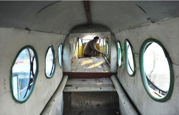 Li Jingchun, a farmer, works inside his self-made aircraft near the roof of his house in Xiahe village