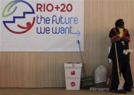 Uma faxineira fala em seu celular durante uma pausa, próximo a um logotipo da Rio+20, na entrada do Pavilhão Brasil no Rio de Janeiro, 18 de junho de 2012. REUTERS/Nacho Doce