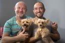 Julian Marsh, left, poses with his husband Tray Popov, a Bulgarian grauate student, and their Yorkshire Terriers, Rosie, left, 4, and Phoebe, 4, at their home, Monday, July 1, 2013 in Fort Lauderdale, Fla. They are the first gay couple in the nation to have their application for immigration benefits approved after the Supreme Court ruling on same-sex marriages, their lawyer says. (AP Photo/Wilfredo Lee)