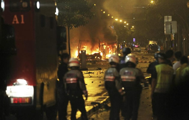 Riot policemen watch burning vehicles during a riot in Singapore's Little India district, late December 8, 2013. A crowd set fire to vehicles and clashed with police in the Indian district of Singapore late on Sunday, in a rare outbreak of rioting in the city state. Television footage showed a crowd of people smashing the windscreen of a bus, and at least three police cars being flipped over. The Singapore Police Force said the riot started after a fatal traffic accident in the Little India area. REUTERS/Dennis Thong/Lianhe Zaobao (SINGAPORE - Tags: CIVIL UNREST TPX IMAGES OF THE DAY) ATTENTION EDITORS - THIS IMAGE HAS BEEN SUPPLIED BY A THIRD PARTY. IT IS DISTRIBUTED, EXACTLY AS RECEIVED BY REUTERS, AS A SERVICE TO CLIENTS. NO SALES. NO ARCHIVES. FOR EDITORIAL USE ONLY. NOT FOR SALE FOR MARKETING OR ADVERTISING CAMPAIGNS. SINGAPORE OUT. NO COMMERCIAL OR EDITORIAL SALES IN SINGAPORE