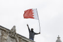 A man waves a flag during a protest from the roof of the Bahrain Embassy in London, Monday, April 16, 2012. The banner, draped over the top of the embassy, carried pictures of imprisoned hunger striker Abdulhadi al-Khawaja and senior Shiite opposition leader Hassan Mushaima. Bahrain has been gripped by a 14-month-old uprising aimed at weakening the powers of the kingdom's Sunni monarchy and the Gulf state has recently seen a spike in violence.(AP Photo/Kirsty Wigglesworth)