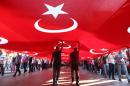 People hold aloft giant Turkish national flags as they participate in a demonstration to condemn terrorism and attacks against security forces, in Ankara on September 17, 2015