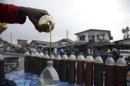 A Nigerian oil dealer pours gasoline into bottles at a road-side market in the commercial capital of Lagos