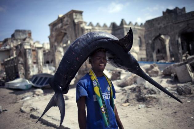 صياد صومالي يحمل سمكة عملاقة بطريقة غريبة