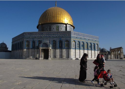 In this Wednesday, April 25, 2012 photo a Palestinian family walks past the Dome of the Rock Mosque in the Al Aqsa Mosque compound in Jerusalem's Old City. After decades of shying away from an ancient pilgrimage route, Muslims are visiting Jerusalem to pray at Islam's third-holiest site and walking straight into a clash between religious clerics, who say such visits are forbidden, and Palestinian leaders urging them to come. (AP Photo/Diaa Hadid)