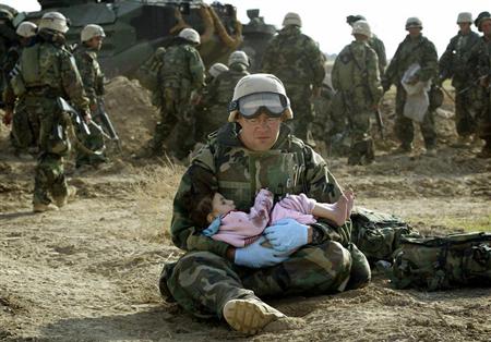 U.S. Navy Hospital Corpsman HM1 Richard Barnett, assigned to the 1st Marine Division, holds an Iraqi child in central Iraq in this March 29, 2003 file photo. REUTERS/Damir Sagolj