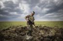 FILE - In this Monday, June 15, 2015 file photo, a Ukrainian serviceman investigates a crater left by a Grad rocket in the village of Toshkivka, Luhansk region, eastern Ukraine. (AP Photo/Evgeniy Maloletka, File)