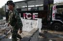 A soldier walk past a destroyed police truck near Government House in Bangkok