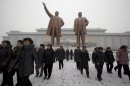 North Koreans leave after laying flowers to show respect to the statues of late North Korean leaders Kim Il Sung, left, and Kim Jong Il at Mansu Hill as it snows in Pyongyang, North Korea, Friday, Dec. 21, 2012. (AP Photo/Ng Han Guan)