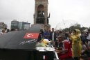 A musician plays the piano as a protester holds an umbrella to protect him from the rain under the monument of Mustafa Kemal Ataturk, founder of the modern Turkey, at Taksim Square in Istanbul Friday, June 14, 2013. Five people, including a police officer, have died and over 5,000 protesters and 600 police have been reported injured in clashes around the country. A meeting between Prime Minister Recep Tayyip Erdogan and representatives of anti-government protesters ended early Friday without a clear resolution on how to end the occupation of a central Istanbul park that has become a flashpoint for the largest political crisis of his 10-year rule. (AP Photo/Thanassis Stavrakis)