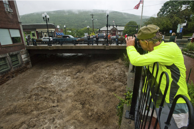 Mel Martin joins a crowd watching the raging Whetstone Brook surge over the falls in downtown Brattleboro, Vt. on Sunday, Aug. 28, 2011. The remnants of Hurricane Irene dumped torrential rains on Verm