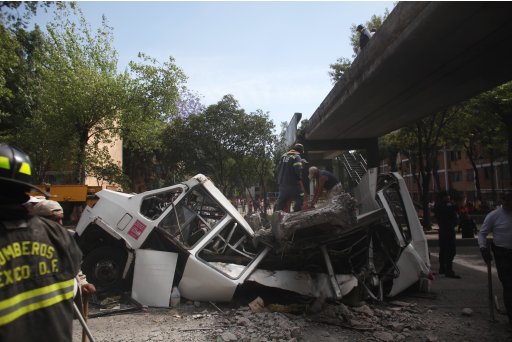 Firefighters work to remove a cement beam that fell from a bridge onto a public bus after an earthquake was felt in Mexico City Tuesday March 20, 2012. A strong 7.4-magnitude earthquake hit central and southern Mexico on Tuesday, collapsing at least 60 homes near the epicenter and a pedestrian bridge in the capital where people fled shaking office buildings. There were no passengers in the mini-bus and the driver suffered minor injuries, according to firefighters. (AP Photo/Alexandre Meneghini)