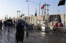 A woman walks near the site of a bomb attack in Baghdad's Doura District
