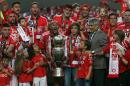 Young Benfica supporters brothers Goncalo and Tomas Magalhaes, lower row third and fourth right, stand next to Benfica's captain Luisao, from Brazil, as he holds the trophy on the stand at the end of the Portuguese league soccer match between Benfica and Maritimo at the Benfica's Luz stadium, in Lisbon, Portugal, Saturday, May 23, 2015. Tomas and Goncalo are the children of Jose Magalhaes who was beating and arrested by a policeman in front of them last Sunday outside a stadium after a Benfica match in Guimaraes, north Portugal, sparking a national scandal. Benfica won its 34th Portuguese league soccer title, second in a row, ahead of runners-up Porto. (AP Photo/Francisco Seco)