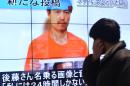 A pedestrian looks at a large screen in Tokyo on January 28, 2015 showing television news reports about Japanese hostage Kenji Goto who has been kidnapped by the Islamic State group