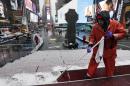 Francisco Mathurine, of the Times Square Alliance, clears snow from the steps in Father Duffy Square in New York, Monday, Jan. 26, 2015. Officials cautioned Northeast residents to not be misled by a relatively smooth Monday morning commute, and pressed their cautions to prepare for a "crippling and potentially historic" storm that could bury communities from northern New Jersey to southern Maine in up to 2 feet of snow starting later in the day. (AP Photo/Richard Drew)