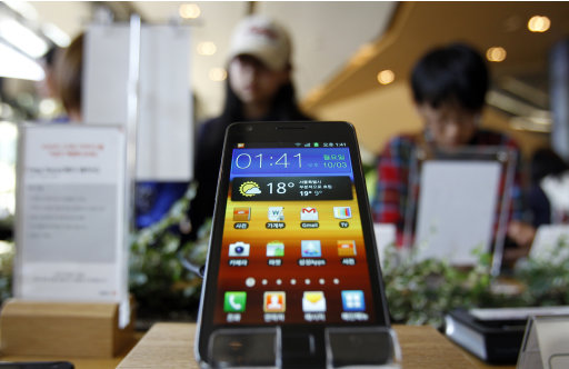 Visitors look at mobile products near the Samsung Electronics smart phone Galaxy S II at a showroom in Seoul, South Korea, Monday, Oct. 3, 2011. If Samsung is to live up to the vaulting ambitions of its homeland and its top executives, many feel it must move beyond being a highly efficient imitator to creating products so original and seductive in function and design they become icons of consumer culture. (AP Photo/Lee Jin-man)
