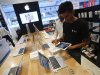 A salesperson unpacks an Apple iPad Mini to test it for a customer in the Apple specialty section of a Croma retail store in Mumbai