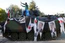 A man poses on an Armored Vehicle with portraits of Turkish President Tayyip Erdogan parked outside the parliament building in Ankara