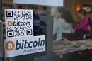 Signs on window advertise bitcoin ATM machine that has been installed in a Waves Coffee House in Vancouver